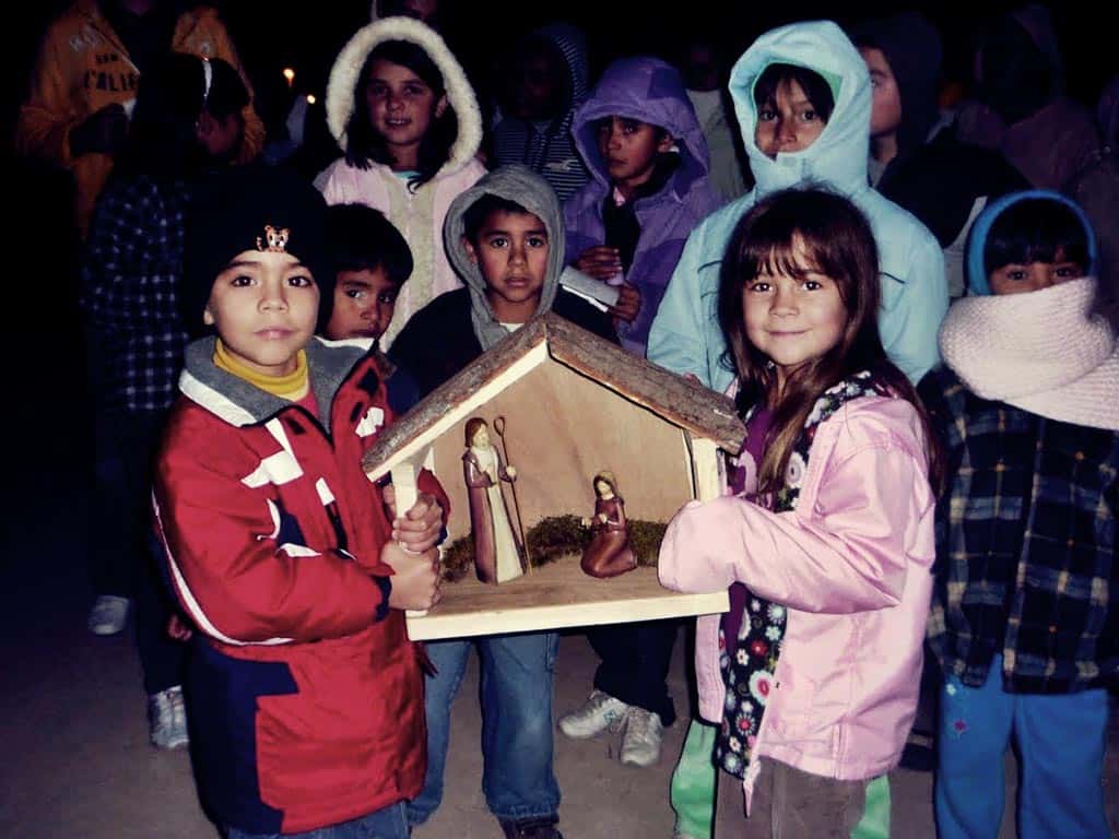 niños celebrando la posada sosteniendo a los peregrinos
