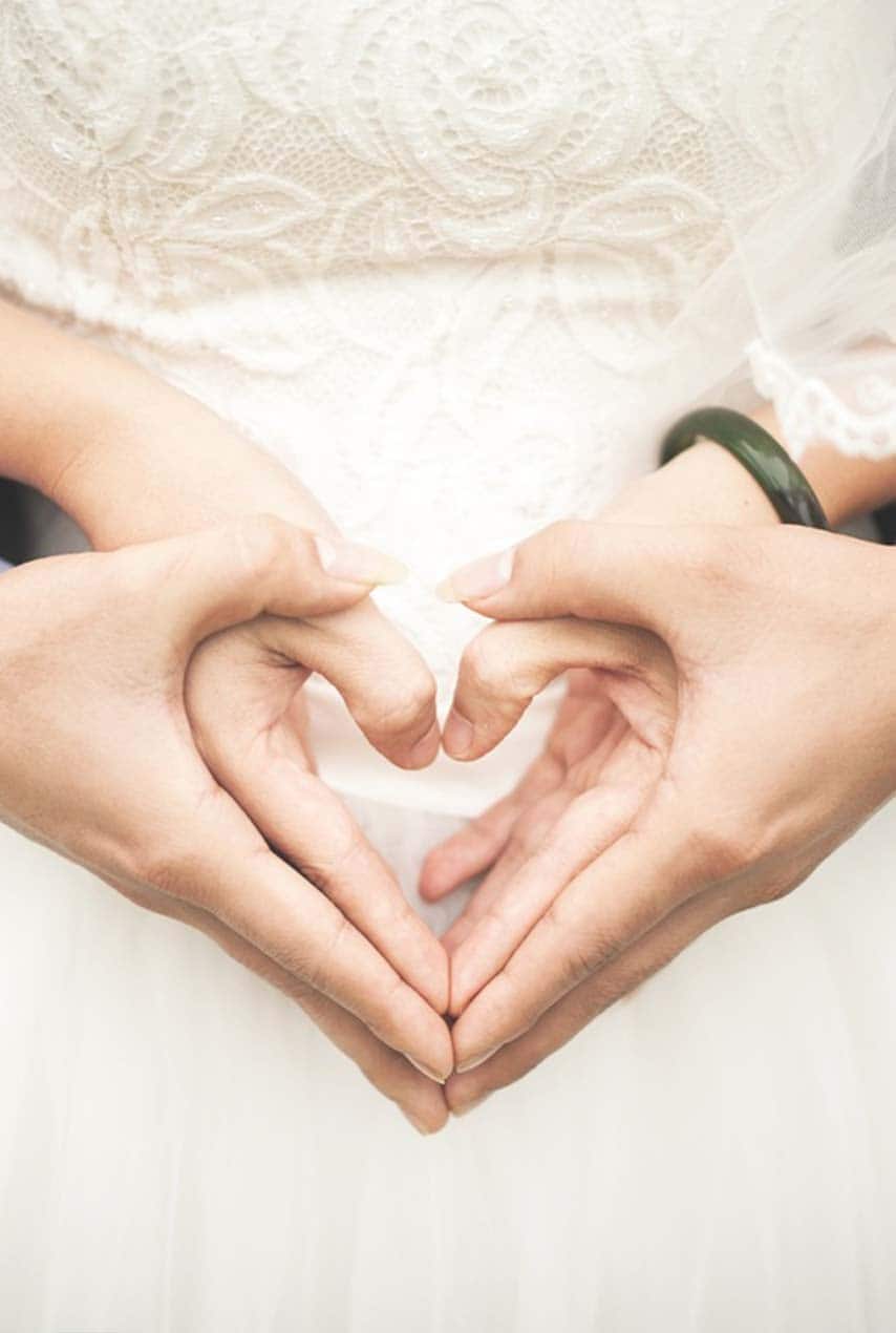 matrimonio recien casado mostrando las manos juntas en forma de corazón